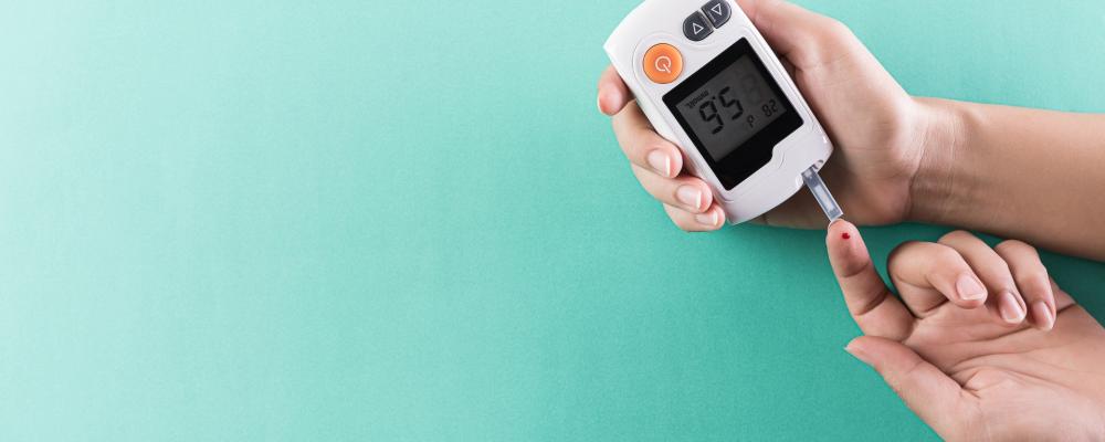 Blood sugar test on finger on teal background