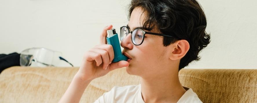 Boy in glasses using inhaler