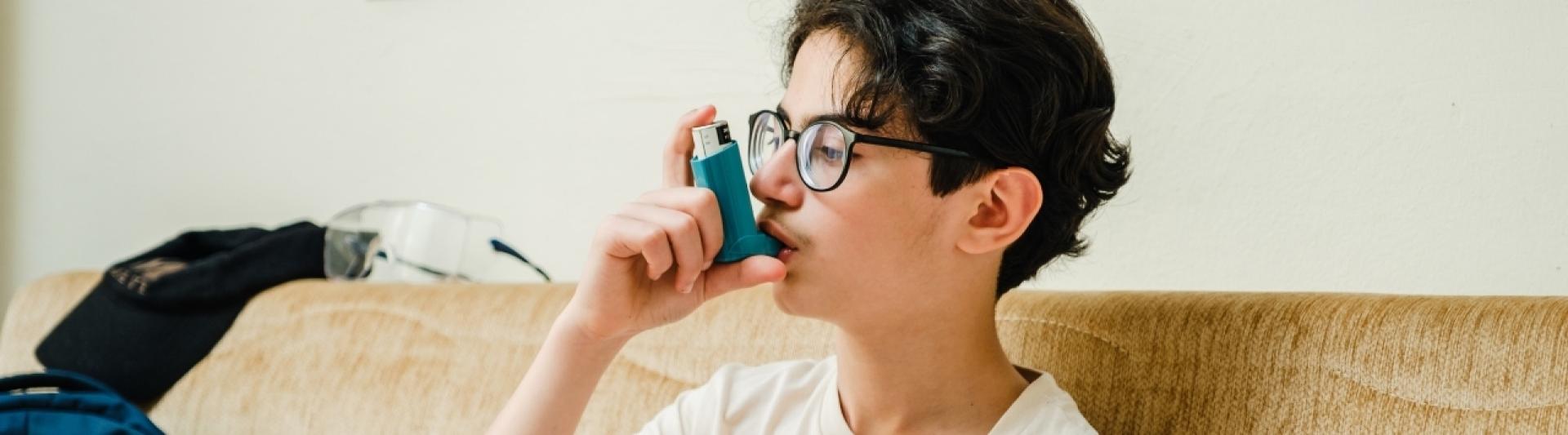 Boy in glasses using inhaler