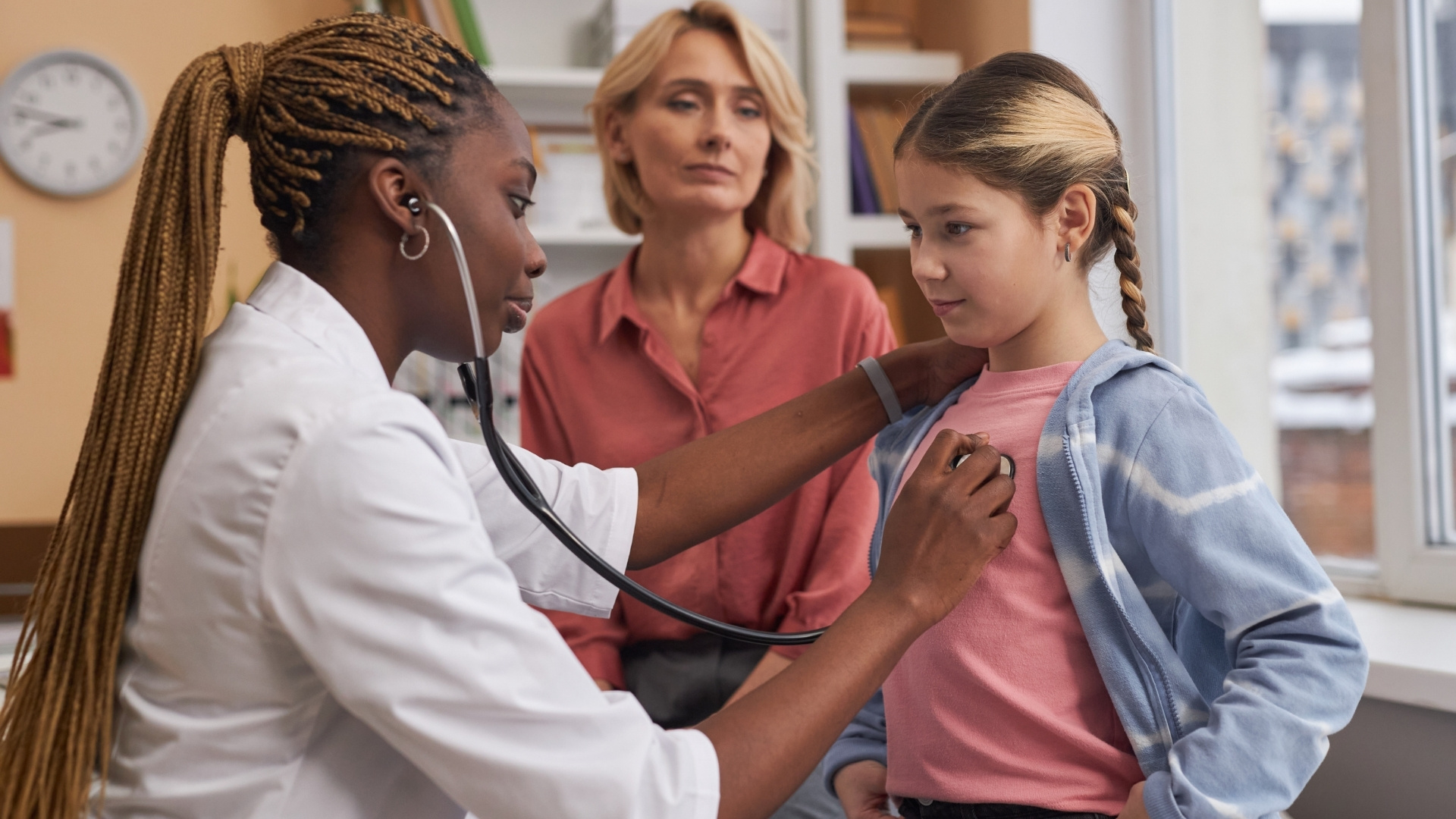 Doctor checking child's breathing with Mum watching