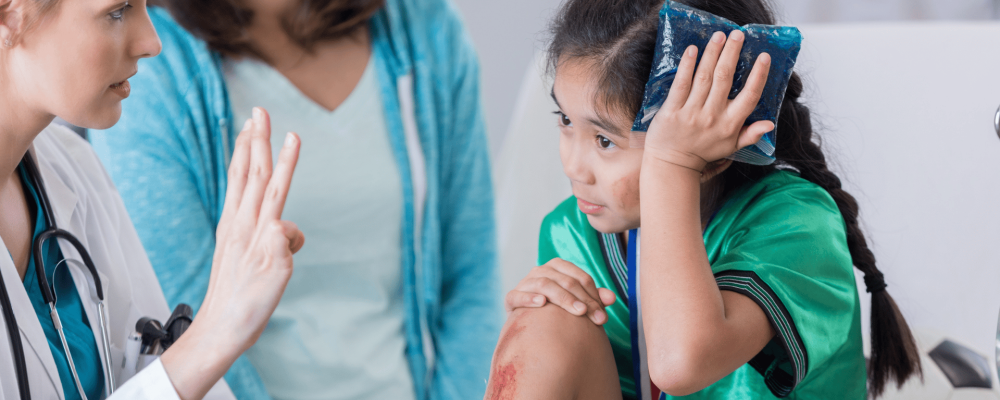 Doctor holding finger up, bruised child holidng ice pack to head