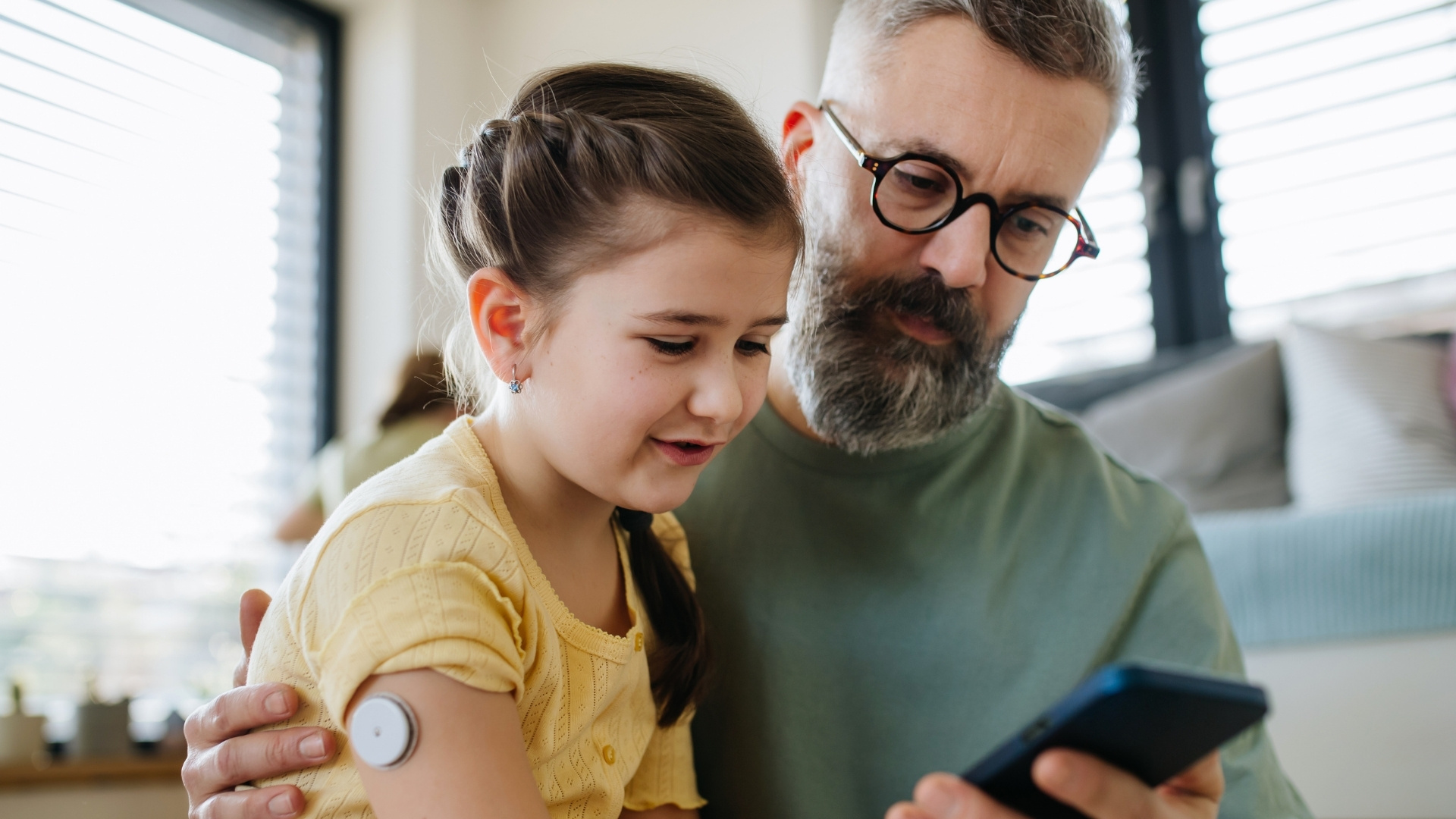 Father and daughter with CGM on arm looking at device