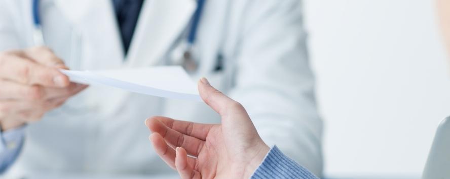GP handing prescription to patient