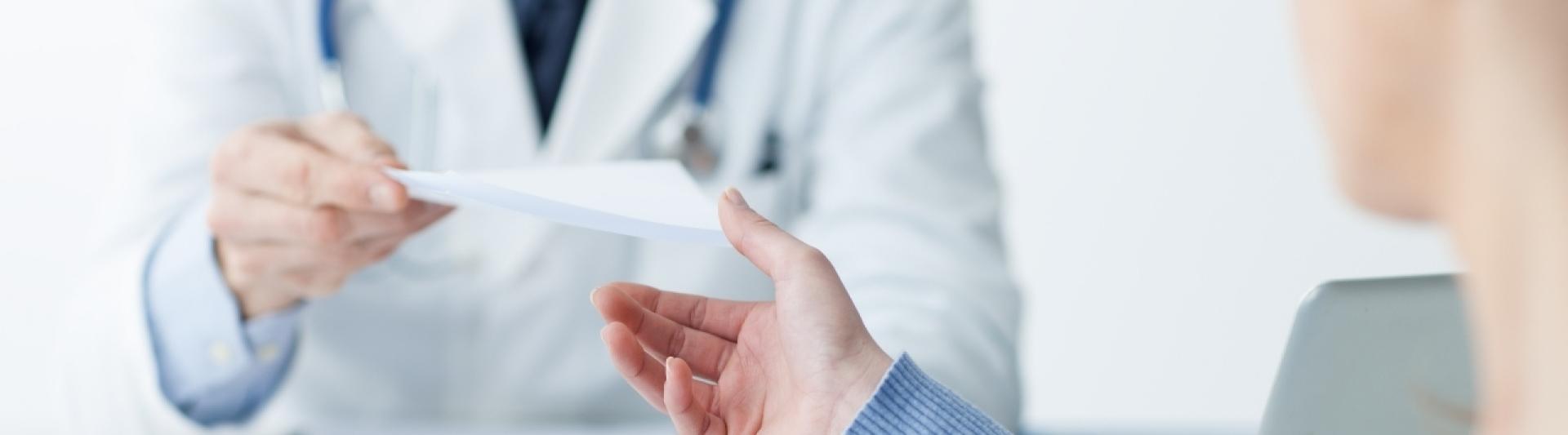 GP handing prescription to patient