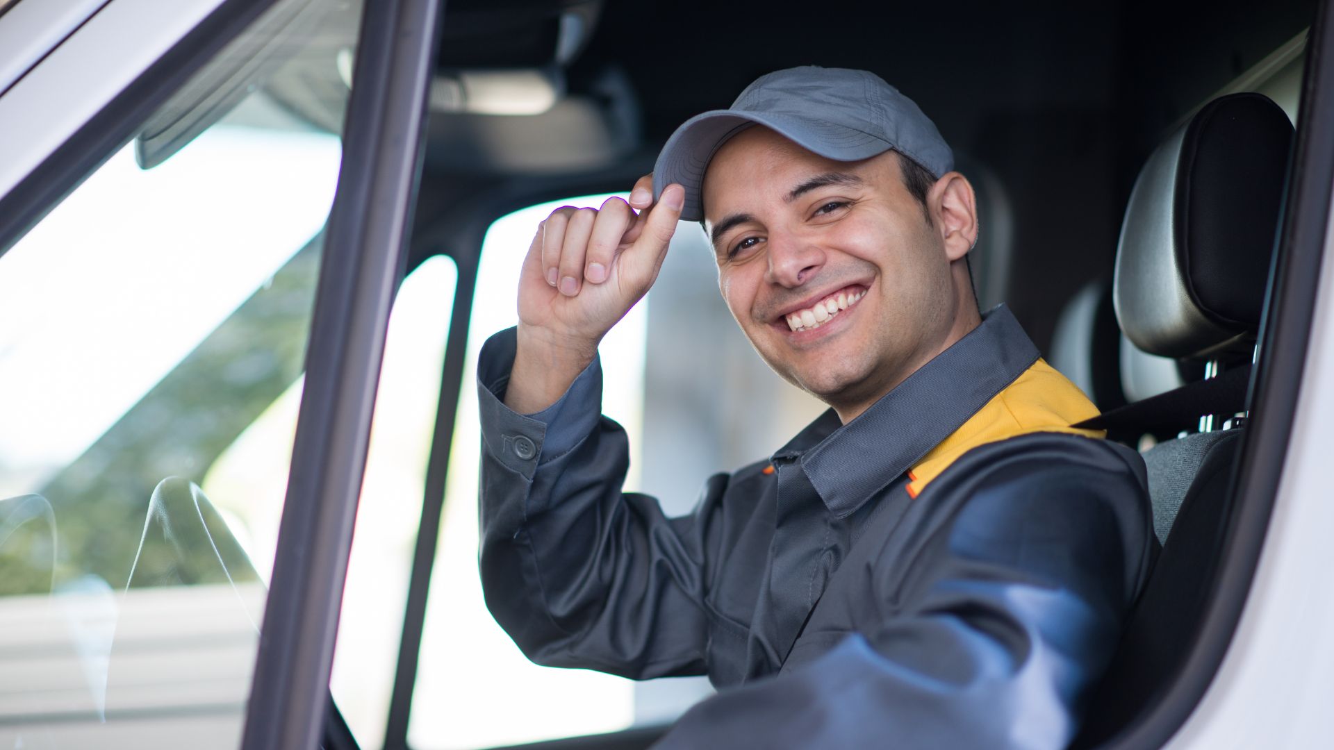 Image of man wearing cap in driver's seat smiling