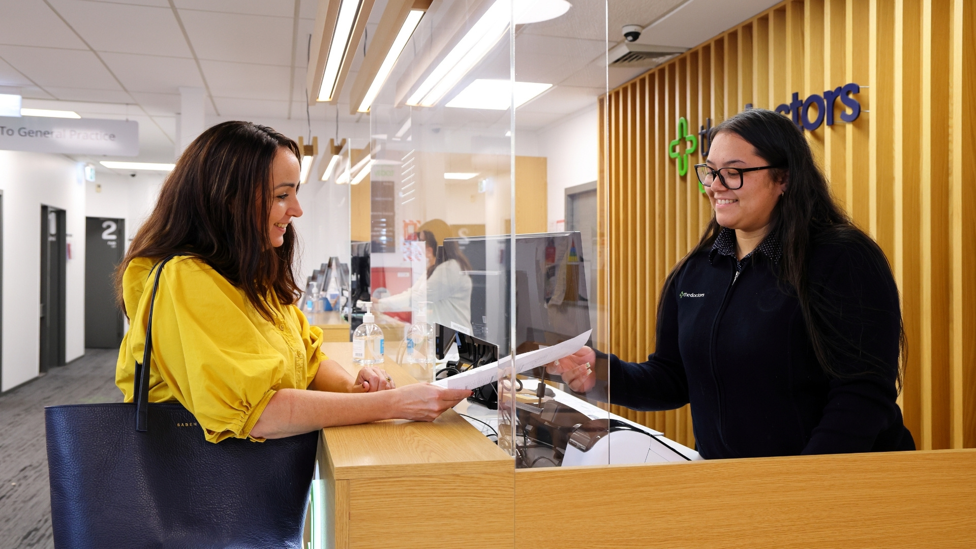 Woman in yellow blouse talking to The Doctors receptionist