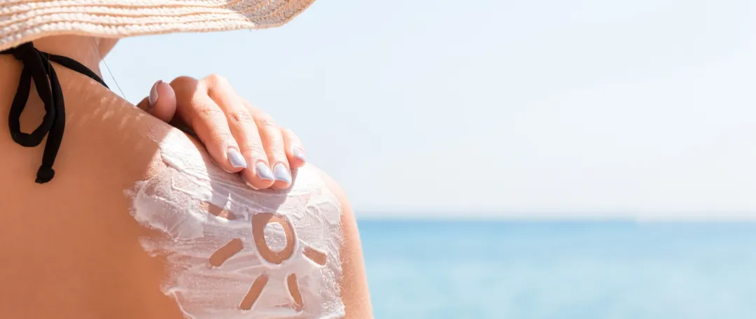 Lady at beach in summer - protect your skin in NZ